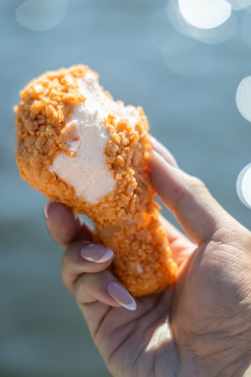 NiceMe Chicken with a bite showing its vanilla center by the water