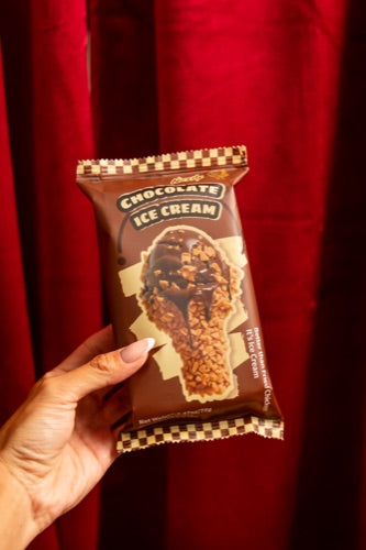 NiceMe Chocolate Chicken individual wrapper against red curtains