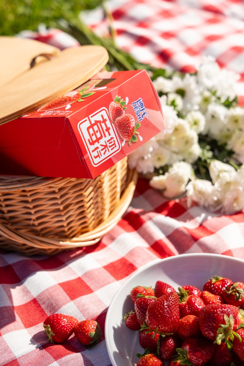 Deshi Strawberry box in a picnic basket beside fresh strawberries